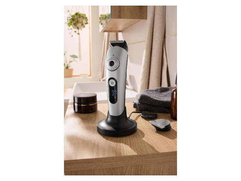 Tondeuse à cheveux et barbe avec écran numérique sur station de charge dans une salle de bain moderne.