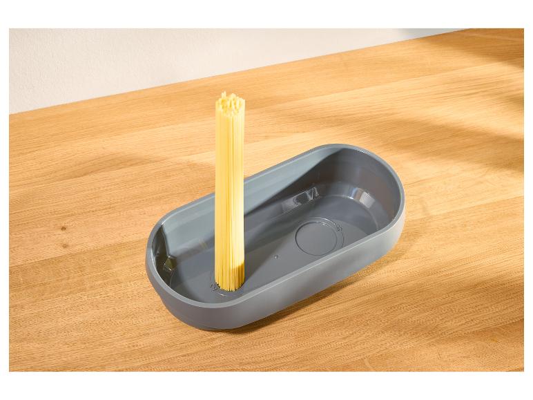 Mesureur de pâtes gris avec des spaghettis crus sur une table en bois.