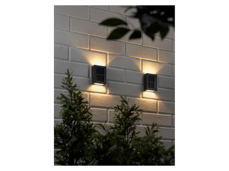 Deux lampes solaires sur un mur de briques blanches.