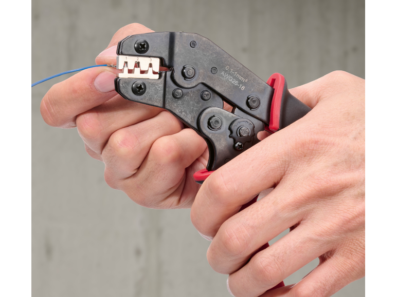 Mains utilisant une pince à sertir pour connecter un fil bleu, avec indications 0.1-1mm² AWG26-18.