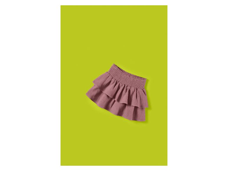 Jupe rose à volants avec taille smockée, posée sur un fond vert lime.