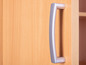 Une poignée de porte argentée sur une porte d'armoire en bois.