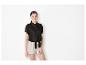 Chemise noire nouée et shorts beiges : look féminin et élégant.