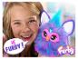 Fille souriante tenant un Furby violet avec des accents bleus.