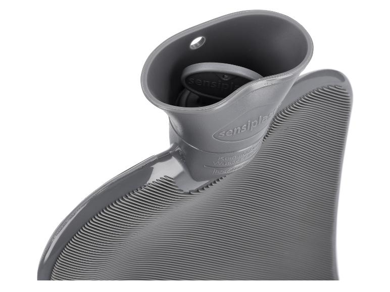 Bouillotte grise côtelée avec le bouchon partiellement visible dans le col de remplissage.