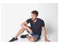 Homme portant un t-shirt henley bleu marine et un short en jean.