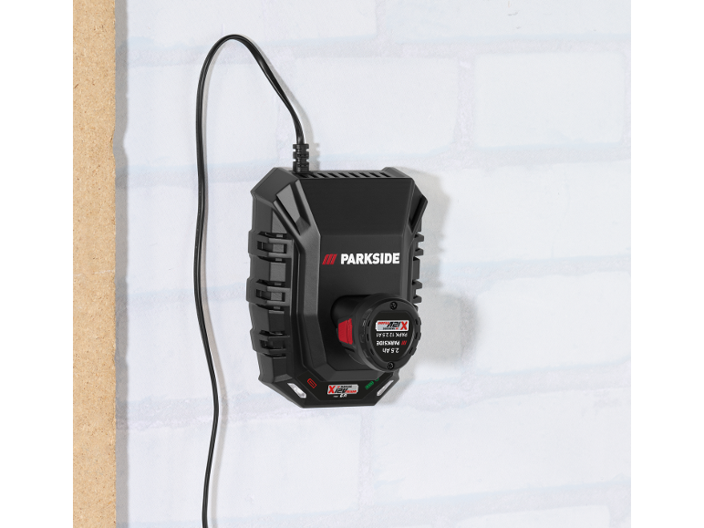 Chargeur de batterie noir avec une batterie 2,5 Ah insérée, monté sur un mur blanc.