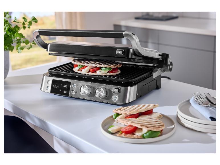 Grill avec deux sandwichs, tomates, mozzarella et basilic, sur une table blanche.
