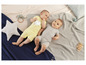 Deux bébés en barboteuses sur une couverture tricotée.