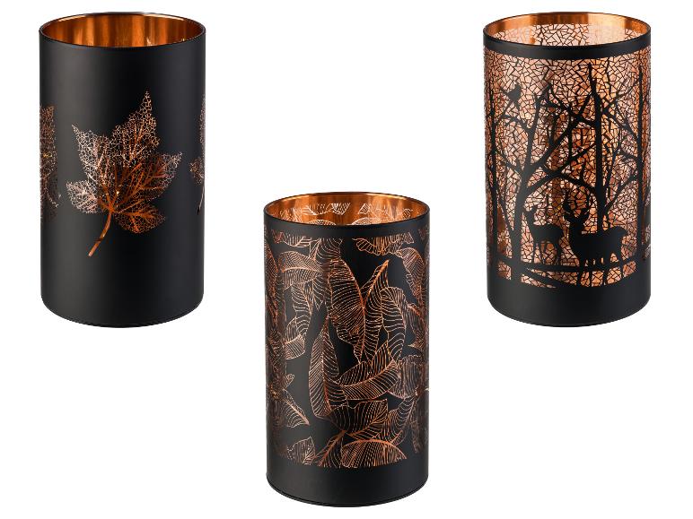 Trois lanternes décoratives noires et cuivrées avec des motifs découpés inspirés de la nature.