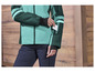 Une femme porte une veste de ski verte et bleue.