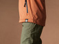 Une veste softshell orange avec un pantalon vert.