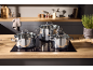 Trois casseroles brillantes avec couvercles en verre sur une plaque de cuisson dans une cuisine moderne.