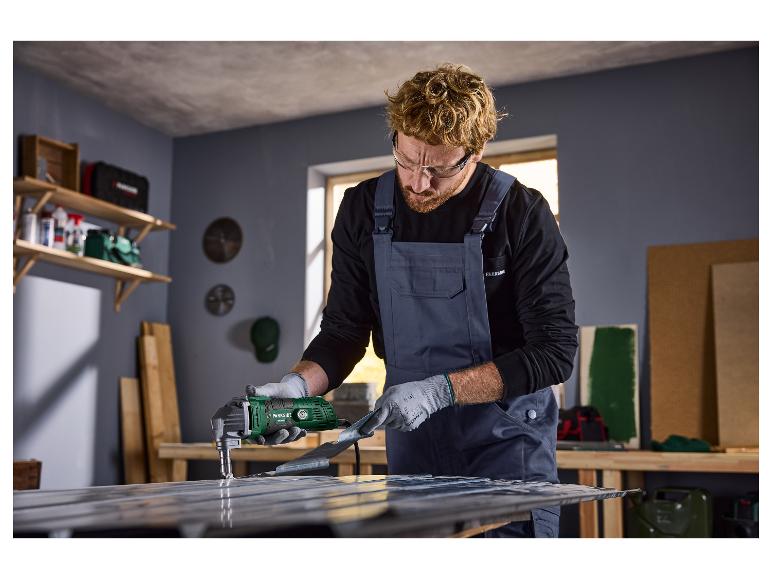Homme en lunettes de sécurité et salopette utilisant une cisaille électrique à métaux Parkside sur tôle.
