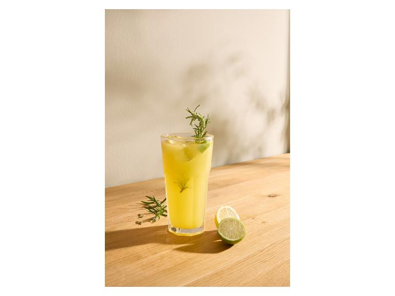 Verre de limonade avec romarin et citron vert sur une table en bois.