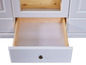 Un tiroir ouvert et une porte en verre d'une commode blanche.