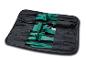 Trousse à outils noire enroulable avec des outils verts de démontage de garnitures et une clé à œil métallique.