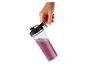 Main tenant une bouteille transparente avec un smoothie violet