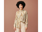 Une femme porte un pantalon beige et une chemise à motif abstrait.