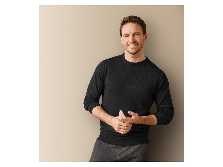 Un homme portant un pull noir à manches longues.