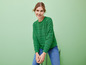 Une femme porte un pull vert et un jean bleu.