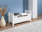 Banc de rangement blanc avec coussin gris, vase avec herbe de la pampa et tapis.