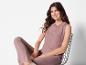 Femme portant un haut et un pantalon roses, assise sur une chaise en métal.