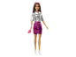 Une poupée Barbie avec une veste argentée, une jupe rose et des chaussures blanches.