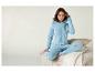 Une femme vêtue d'un pyjama bleu à étoiles est assise sur un canapé.