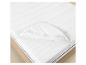 Protège-matelas blanc avec bandes élastiques sur un matelas dans un lit en bois.