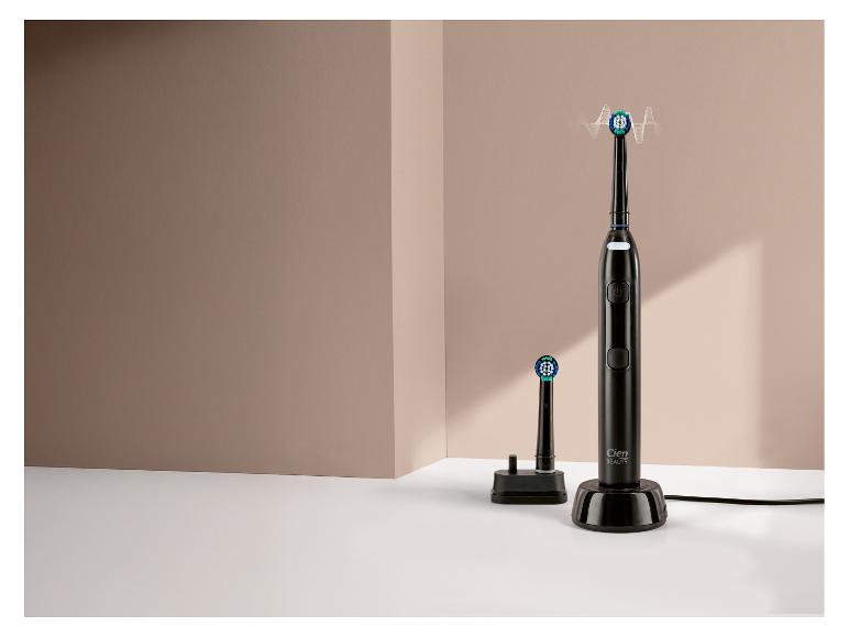 Brosse à dents électrique noire avec chargeur et tête de rechange sur surface blanche