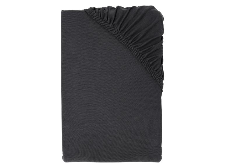 Drap-housse en jersey de coton gris foncé, plié avec des détails élastiques.