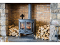 Poêle à bois avec feu allumé, piles de bois de chauffage et accessoires de cheminée.