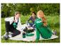 Trois amis en pique-nique, avec des sacs banane verts et un sac isotherme.