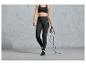 Femme en leggings de sport et soutien-gorge de sport tenant une corde à sauter.
