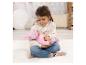 Jeune fille assise sur un tapis blanc, tenant une poupée bébé vêtue de rose.