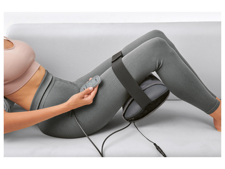 Une femme utilise un coussin de massage Shiatsu pour ses jambes.