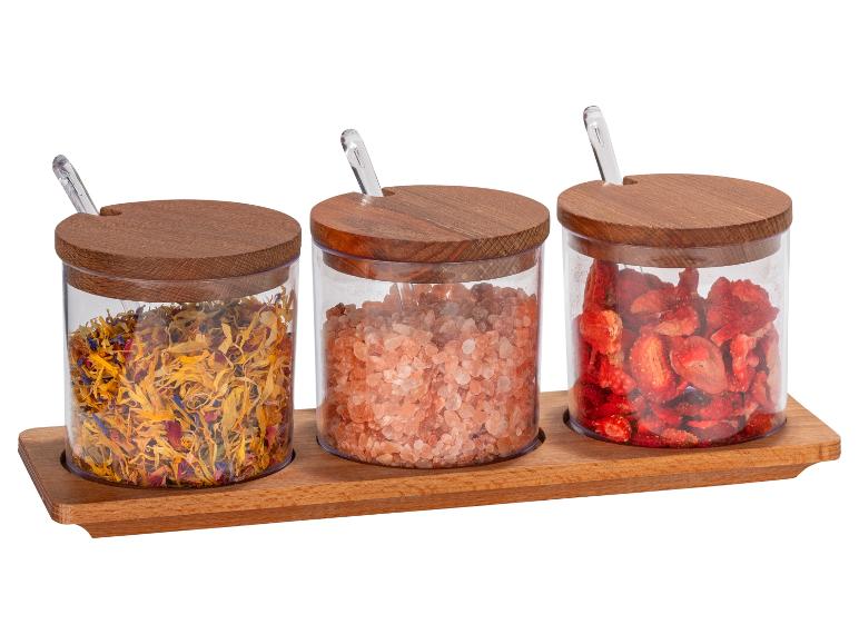 Herbes, sel rose de l'Himalaya et fraises lyophilisées dans des pots en verre avec couvercles en bois.