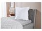 Couette et oreiller matelassés blancs sur un lit gris dans une chambre.