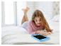 Une fillette utilise une tablette d'écriture LCD bleue pour dessiner sur son lit.