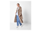 Modèle portant un trench beige et des baskets blanches.