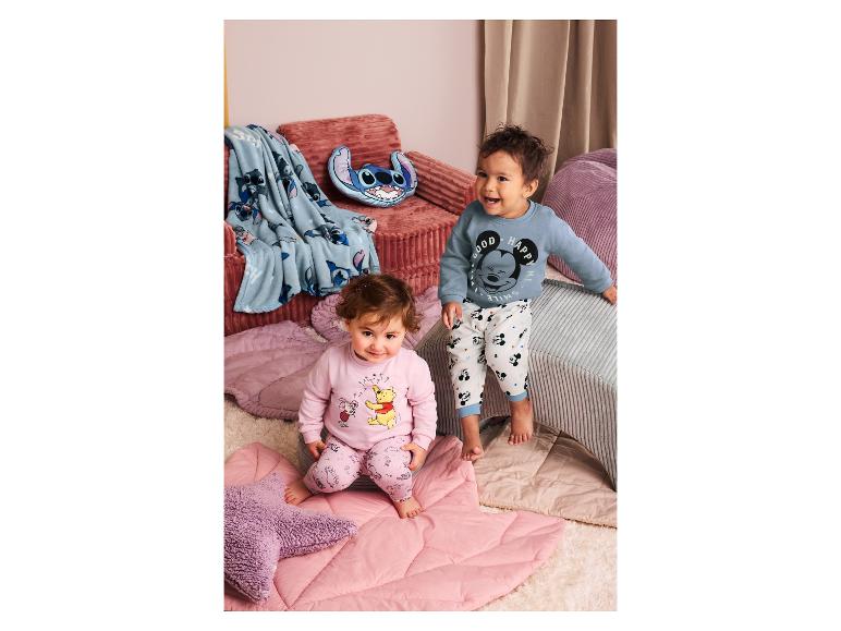 Deux tout-petits en pyjama, l'un en rose avec Winnie l'Ourson, l'autre en bleu avec Mickey Mouse.