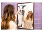 Une femme nettoie un miroir avec un essuie-glace électrique.