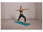 Une femme en soutien-gorge de sport et leggings fait du yoga sur un tapis bleu.