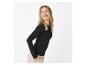 Femme blonde en haut noir à manches longues et pantalon beige, souriante et regardant de côté.