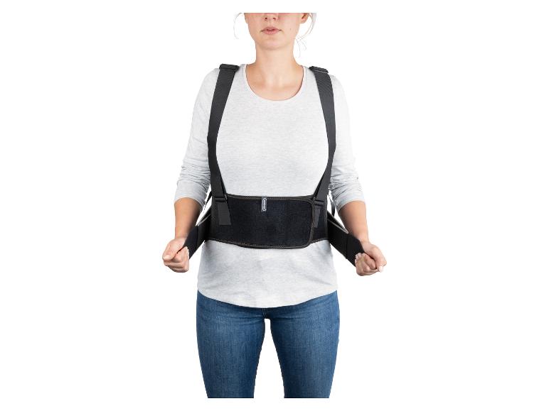 Femme en jean et t-shirt ajustant une ceinture de soutien dorsal noire à bretelles.