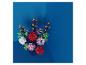 Un bouquet vibrant de fleurs artificielles colorées dans un vase sur fond bleu.