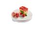 Une part de gâteau aux fraises, des macarons et des framboises sur un piédestal en marbre.
