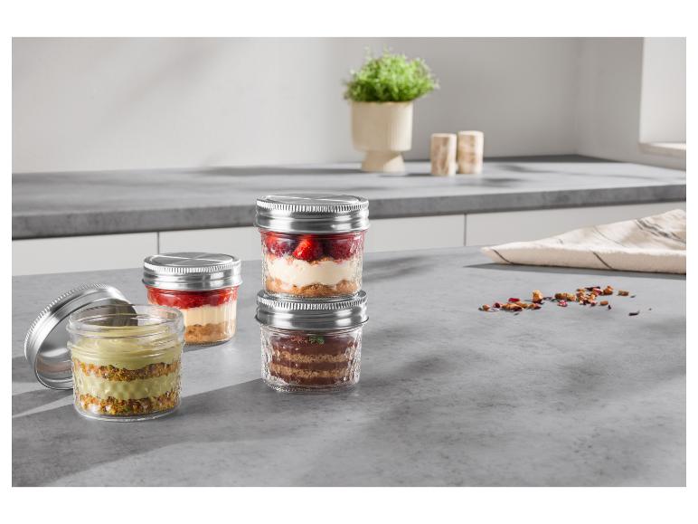 Desserts en bocaux sur un comptoir de cuisine, incluant fraise, pistache et chocolat.