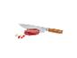 Couteau de chef avec manche en bois, coupant un morceau de viande crue, avec des piments.